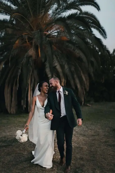 mari et femme à leir mariage sourient en marchand vers l'objectif